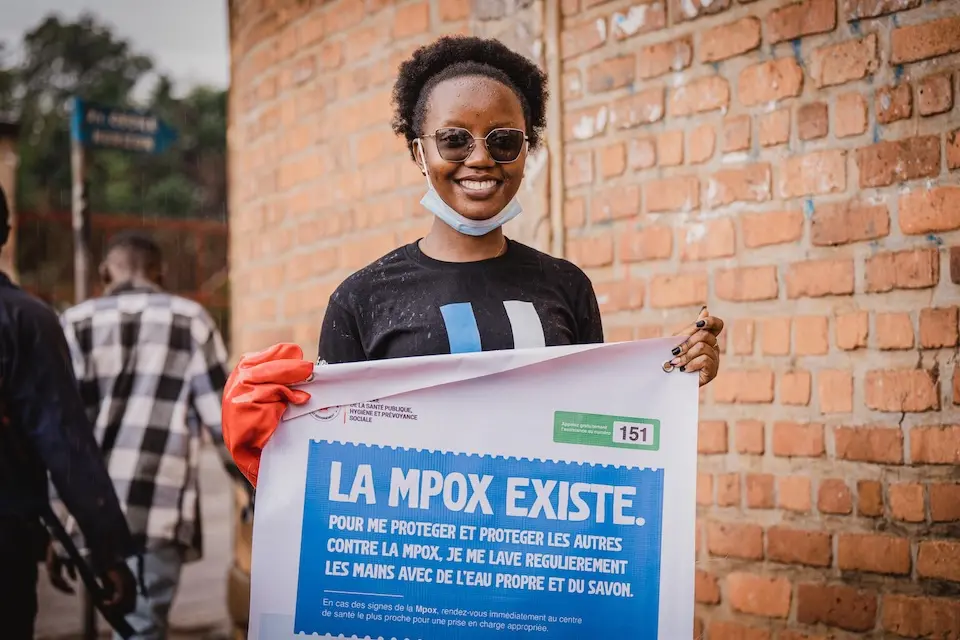 A young woman in Democratic Republic of the Congo holds a sign warning about smallpox