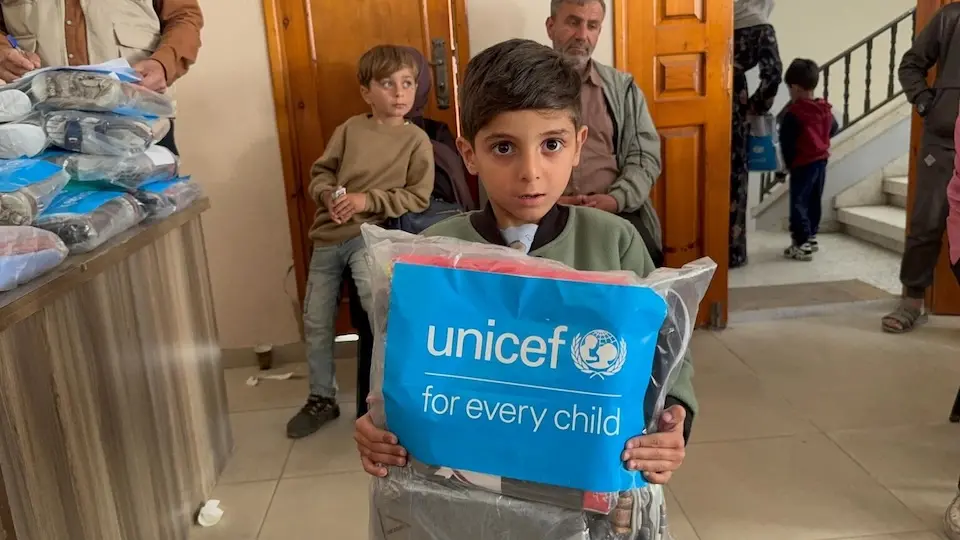 A boy holds a package of summer clothing distributed by UNICEF to the most vulnerable families in Gaza City.