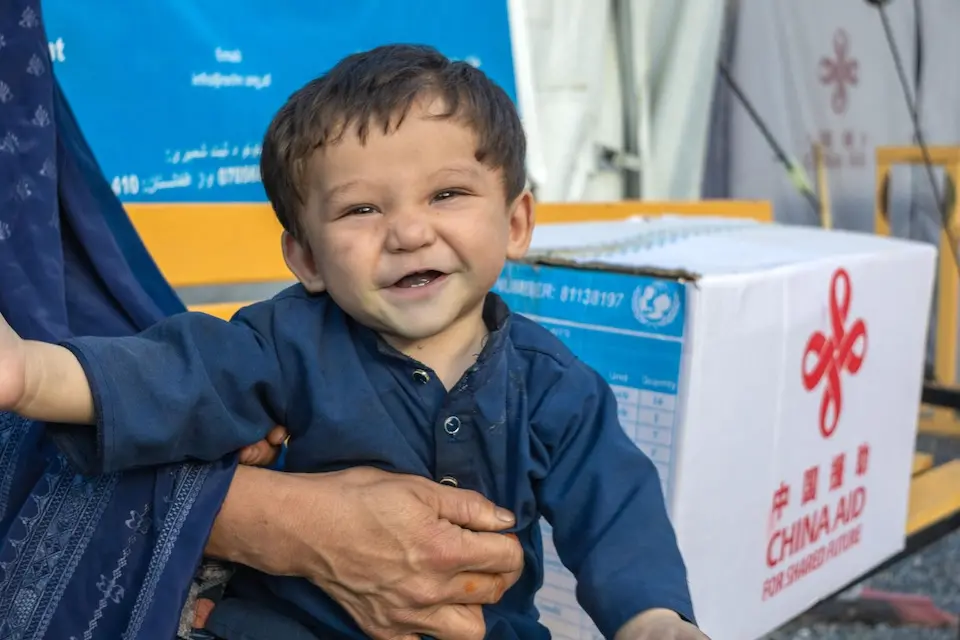 A 10-month-old sits on his mother's lap as she receives a hygiene kit, provided by UNICEF for returnee families at Afghanistan's eastern Torkham border with Pakistan.