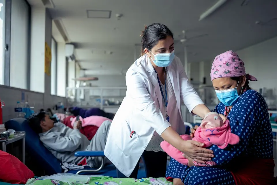 A UNICEF-supported health worker tends to a new mother and baby in a hospital in Kathmandu.