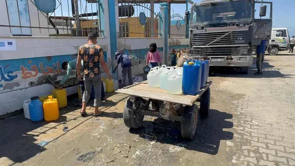 On May 8, 2025, people in Deir al-Balah, located in the central Gaza Strip, gather to fill jerry cans with clean, drinkable water from an operational desalination plant.