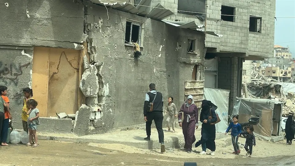 Children and others walk near destroyed buildings in Khan Younis, State of Palestine, on May 12, 2025.