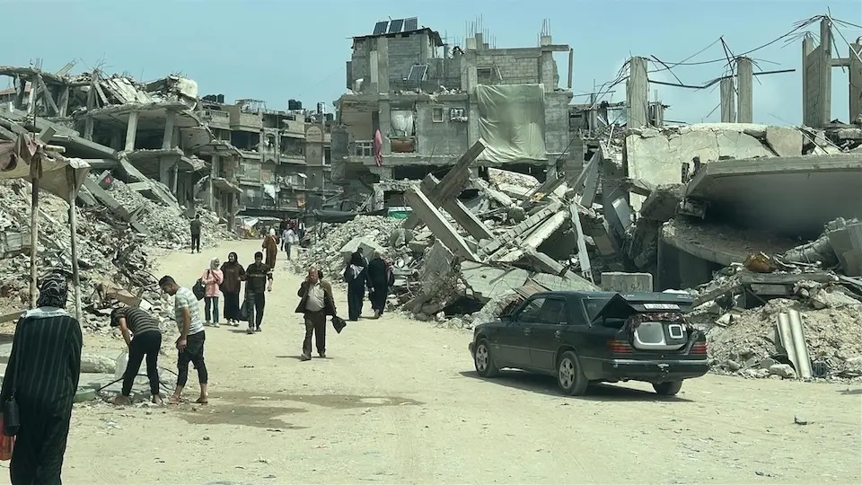 People walk among the ruins in southern Khan Younis on May 12, 2025.