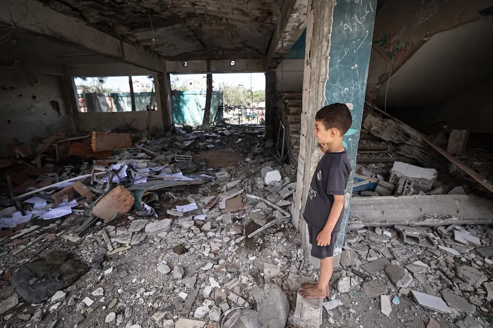A Palestinian child looks at the rubble inside a classroom at a UNRWA school sheltering displaced people after it was directly hit during an air strike on Nuseirat camp.
