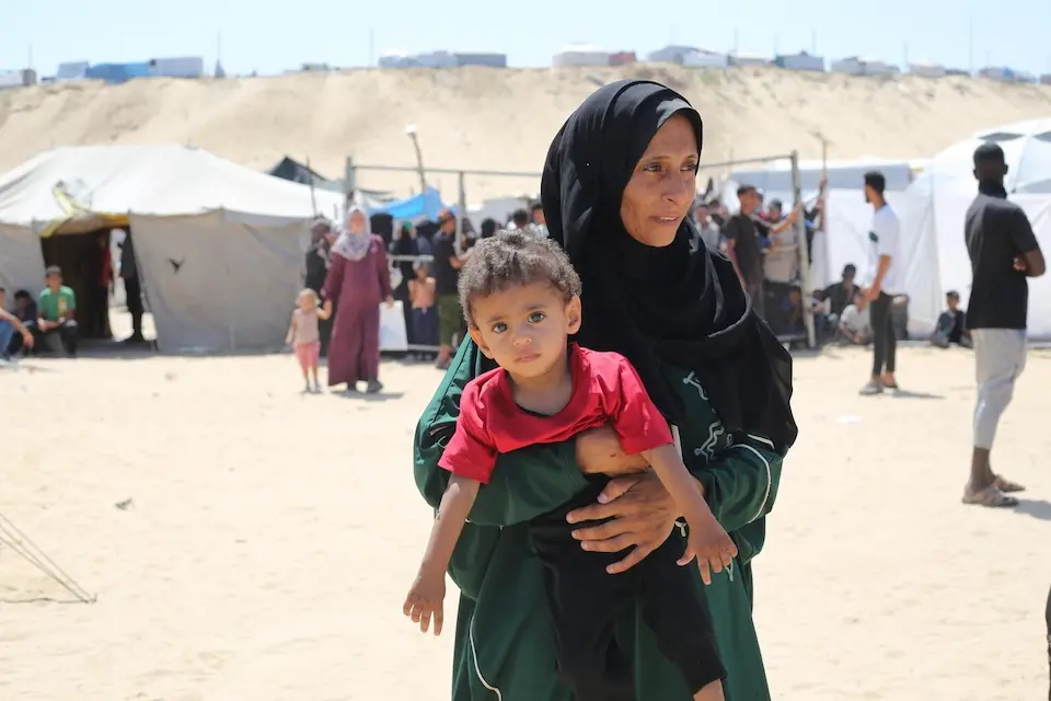 A mother holds her 1-year-old son at a UNICEF-supported malnutrition screening and treatment point in Khan Yunis, southern Gaza Strip.