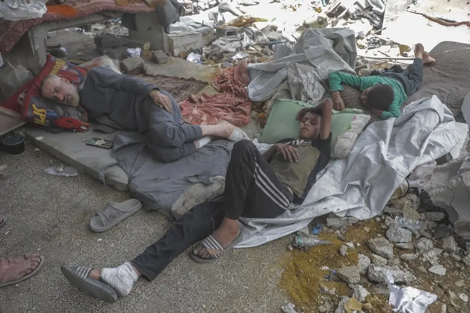 A father and his sons lie among ruins in a schoolyard in Al-Shuja’iya, Gaza Strip.