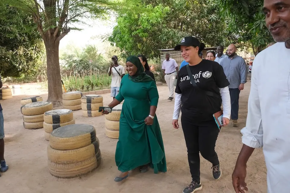 The head of a UNICEF-supported organization in Senegal that teaches young girls life skills walks with a visiting member of UNICEF USA staff.
