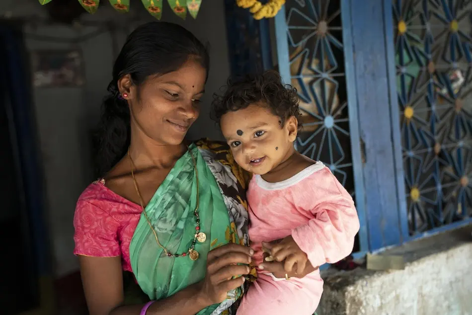 A mother and son play in front of their house in India, where UNICEF helped install a toilet