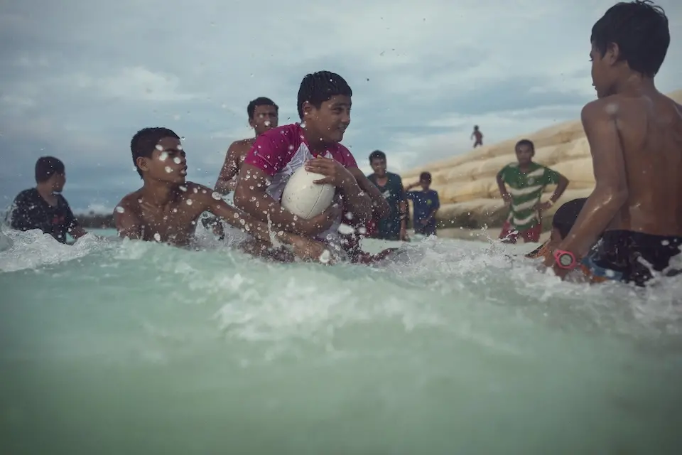 A group of children in Tuvalu play rugby in the water.
