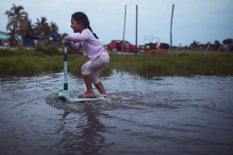 Girl in Tuvalu scoots through flooded waters.