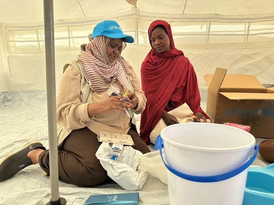 A mother displaced by Sudan conflict receives a dignity kit from UNICEF staff in Kassala state..