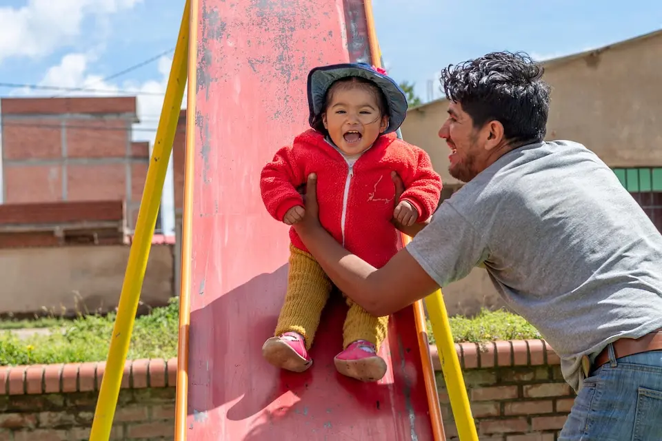 A father helps his 15-month-old daughter down a slide in El Alto, Bolivia.