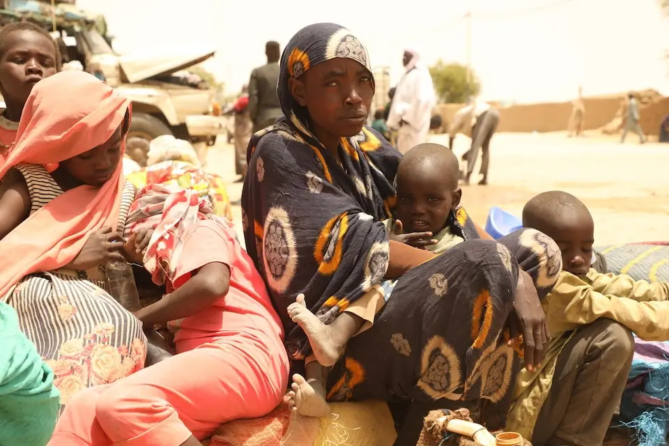 A mother and her children wait in Tiné, Chad to be relocated to a temporary site for refugees.