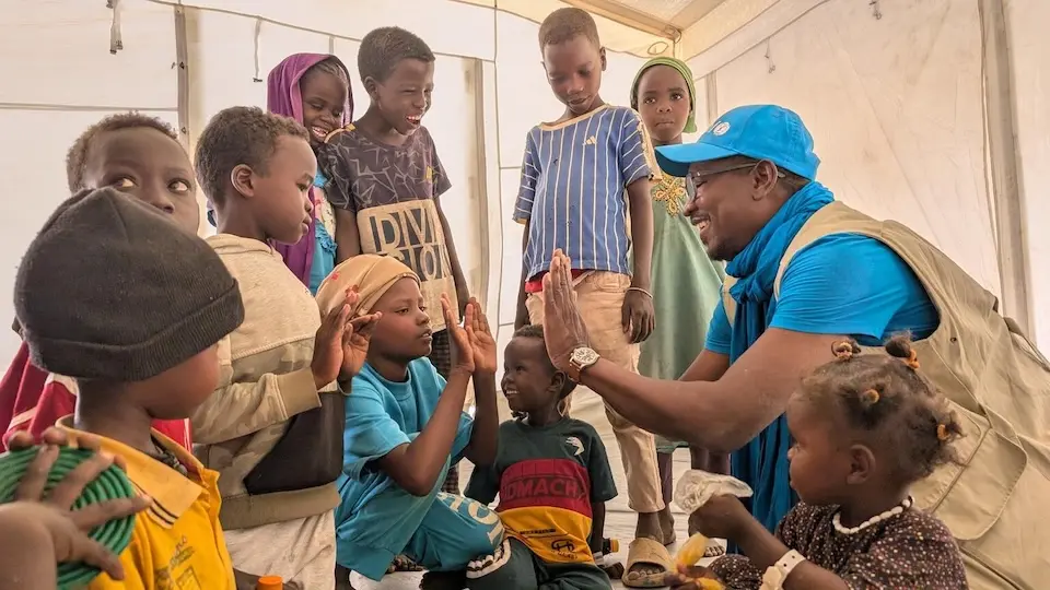 A UNICEF staff member plays with children at the child-friendly space set up by UNICEF in Tiné, at the border with Sudan.