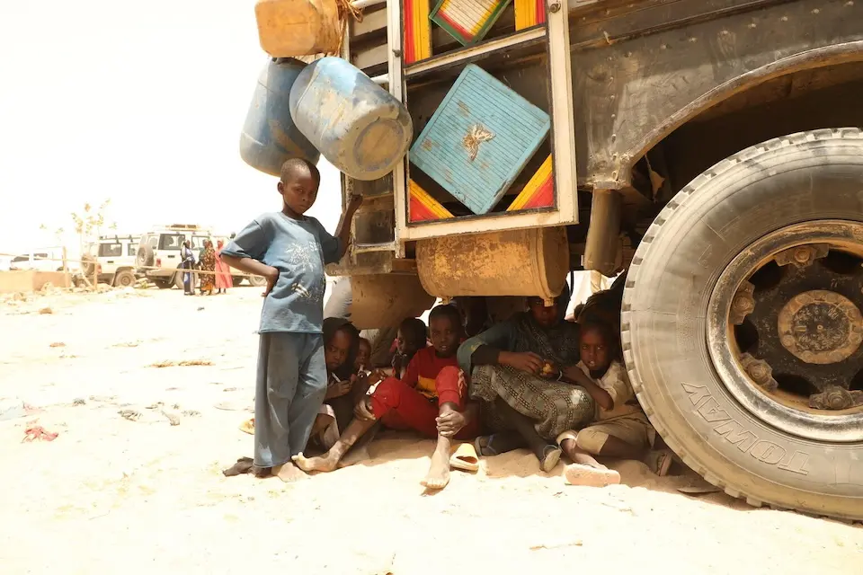 Children fleeing conflict in Sudan take shelter under a truck in eastern Chad.