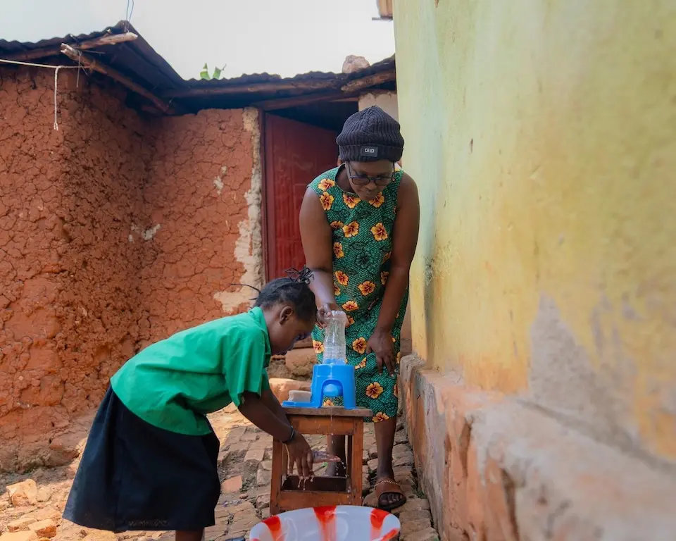A caregiver at an Early Childhood Development Center in Kicukiro District helps children to wash their hands before going home using SATO taps provided by UNICEF.