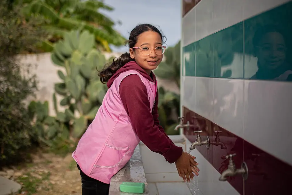 A child washes her hands at school in a sanitary facility repaired by UNICEF.