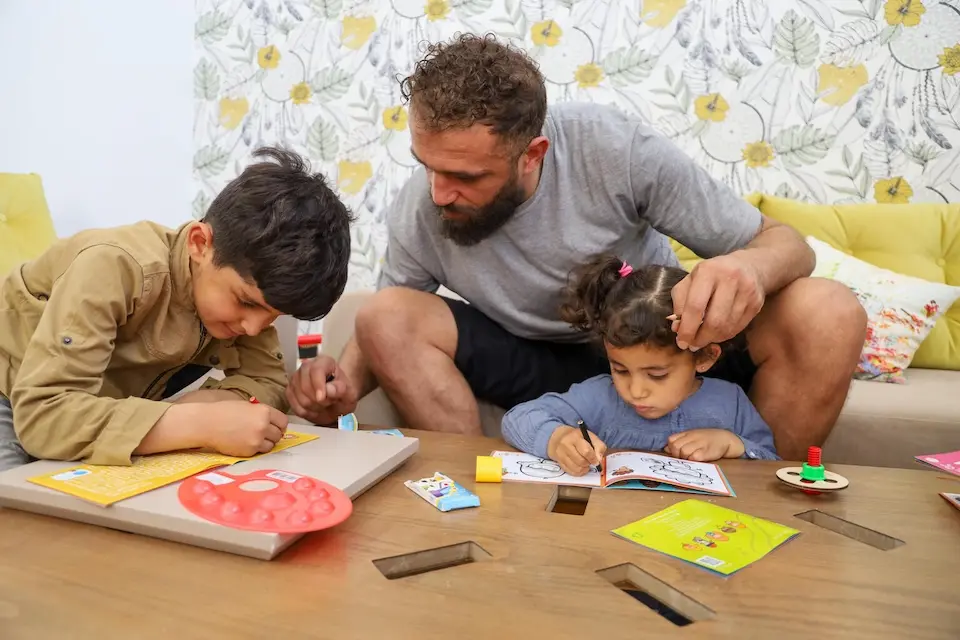 A father and his children learn positive parenting practices at a center supported by UNICEF in Tunisia.