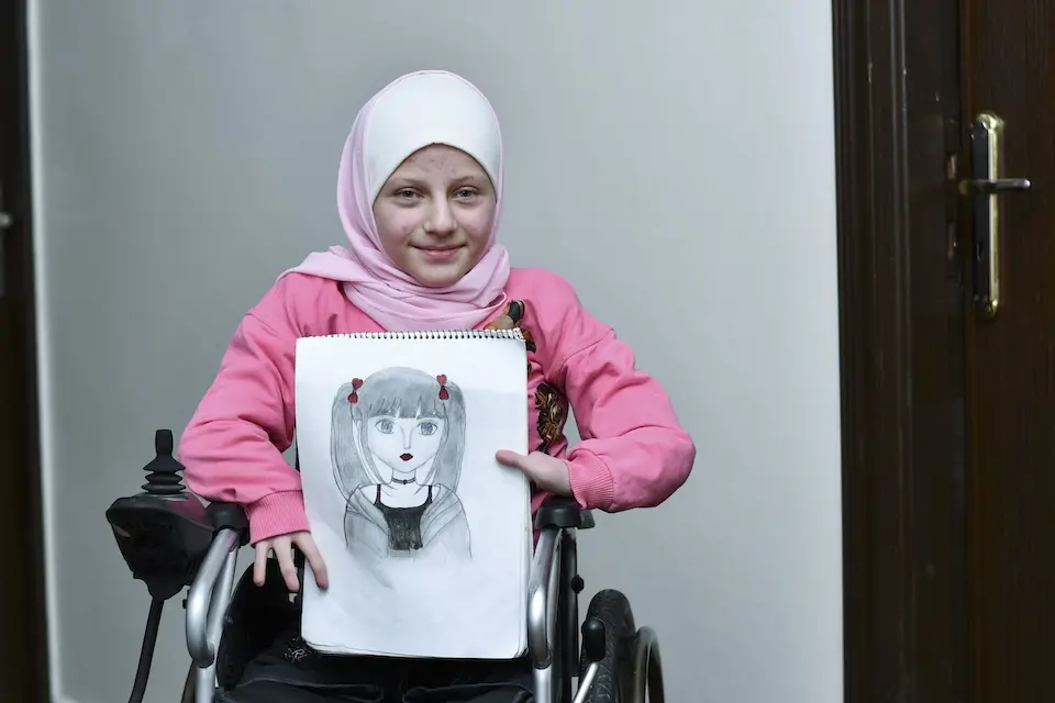 Fatima, 12, holds one of her drawings, at her home in Arbin town, Rural Damascus, Syria.