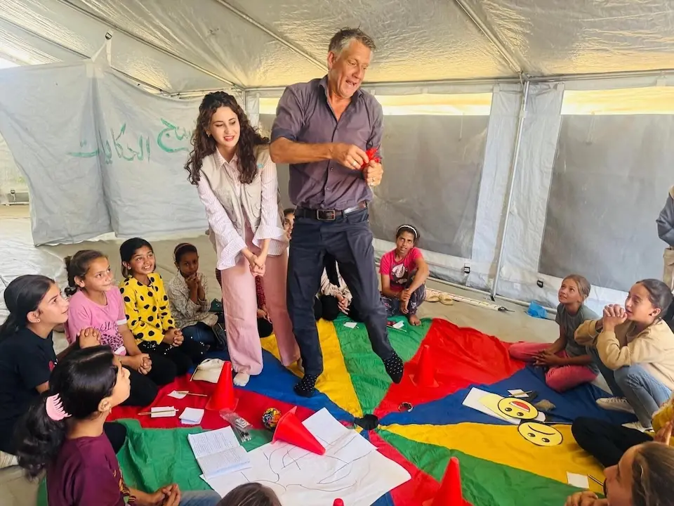 UNICEF staff and Palestinian children take part in a mental health and psychosocial support activity in a tent in Khan Younis.
