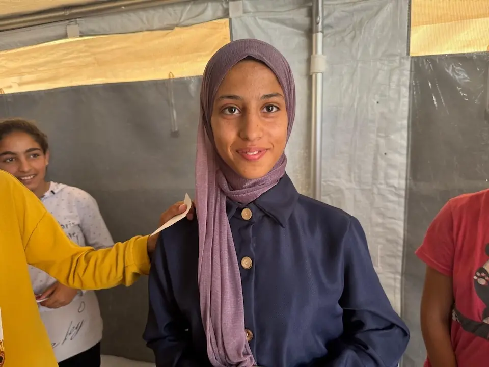 A 13-year-old girl smiles during a UNICEF mental health activity in a tent in Khan Younis, Gaza.