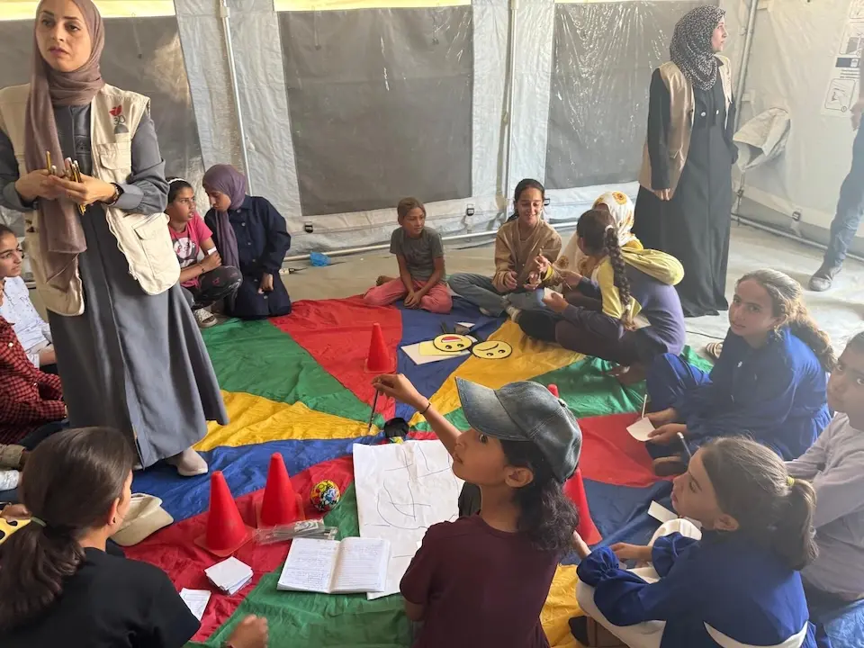 Children sit on the floor in a UNICEF tent during a mental health and psychosocial support session in Khan Younis, Gaza Strip.