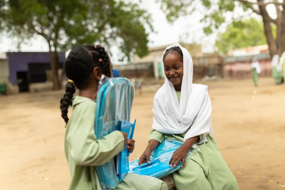 Schoolgirls sit on a bench with their new UNICEF school kits in Blue Nile state, Sudan.