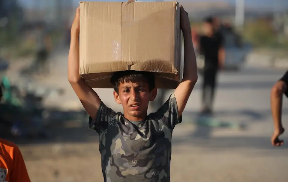 A 13-year-old boy holds a box of food on his head in the Gaza Strip.