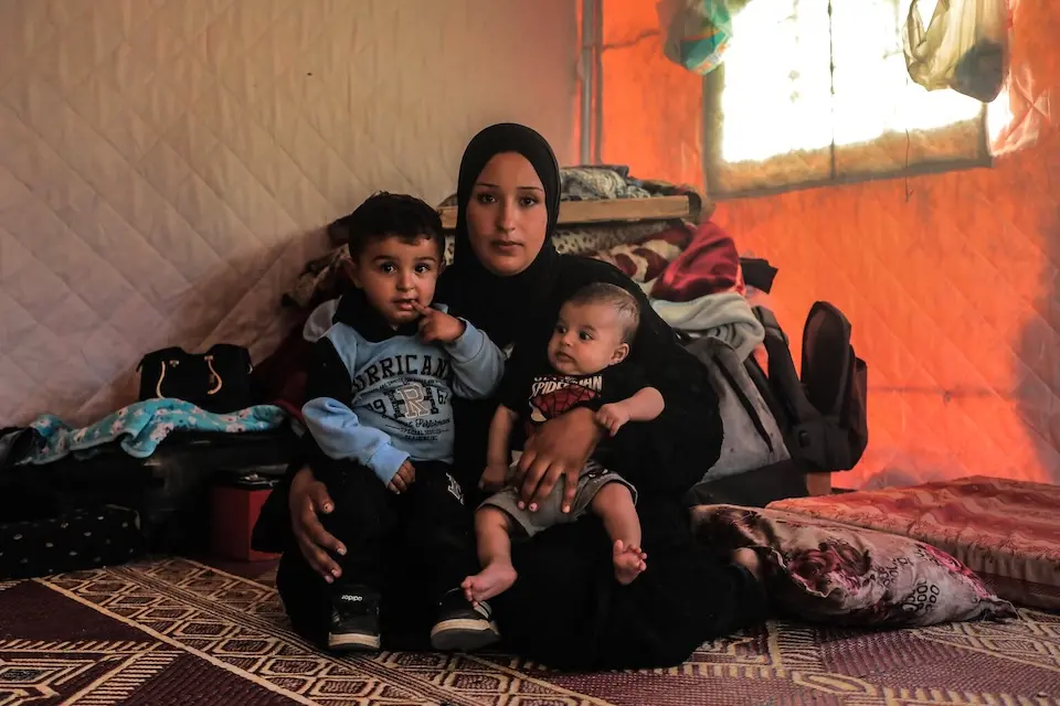 A mother holds two small children on her lap in the Gaza Strip.