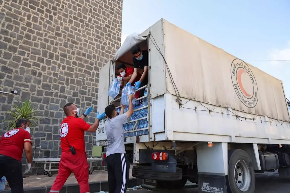 Aid workers unload safe water from a truck, part of the UNICEF-supported emergency response to escalation in hostilities in As-Sweida, southern Syria..