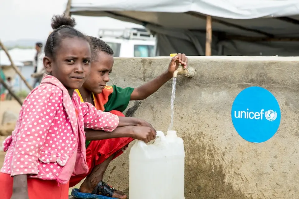 Two children draw water from a UNICEF-supported water source at an IDP camp in Tigray, Ethiopia.