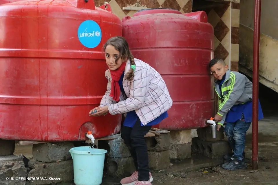 Two children in rural Deir ez-Zor, Syria, wash hands using safe water source UNICEF installed outside their school.