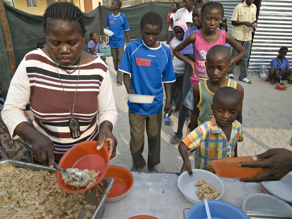 Women volunteers serve food to waiting children, at the Oonte centre for orphans and other vulnerable children (OVCs), in the town of Ondangwa, Namibia. © UNICEF/ UNI2731