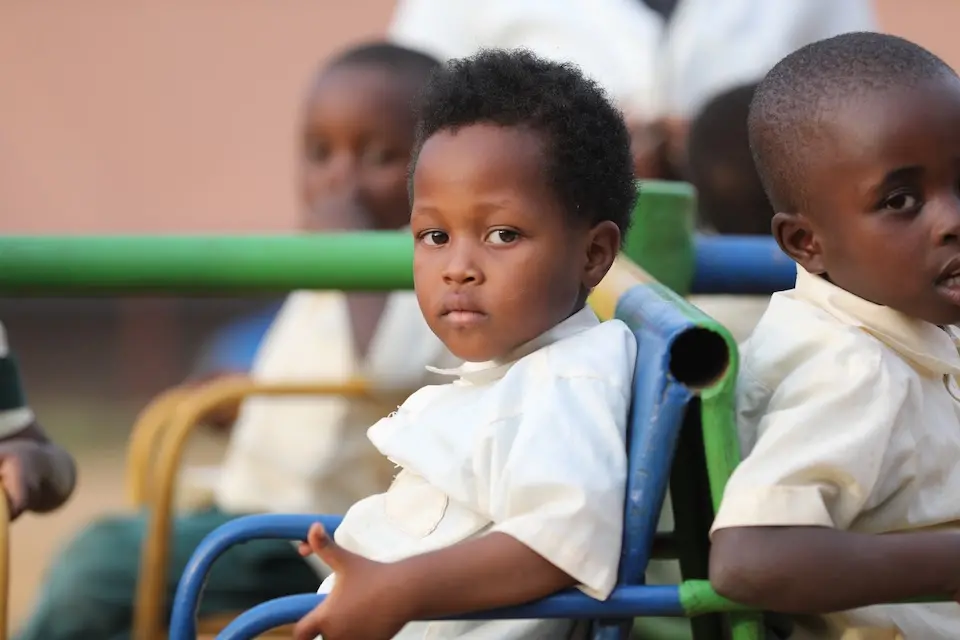 Young girl looking directly into camera, sitting on metal playground equipment