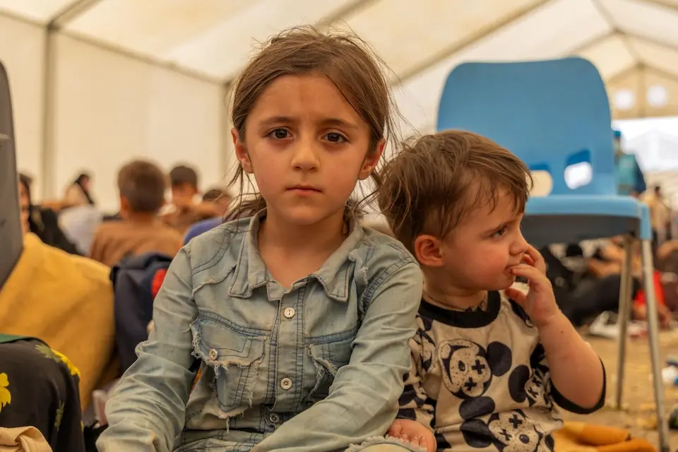 A sister and brother sit inside a large tent set up for Afghan families returning home from Iran at the Islam-Qala border point. 