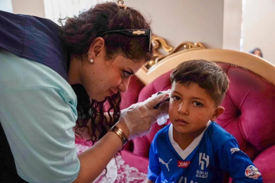 A pediatrician with a UNICEF-supported mobile unit examines a 5-year-old child at a Syrian shelter for displaced families.