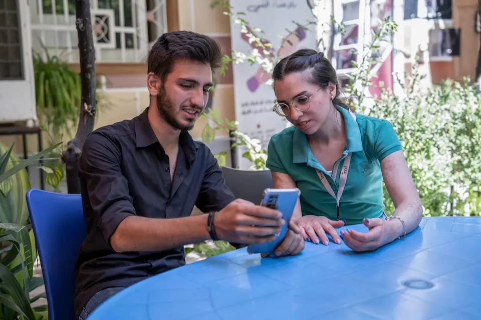 In Jaramana, Rural Damascus, Syria, UNICEF-supported youth Elia, 17, shows a co-worker how to fix a mobile phone.