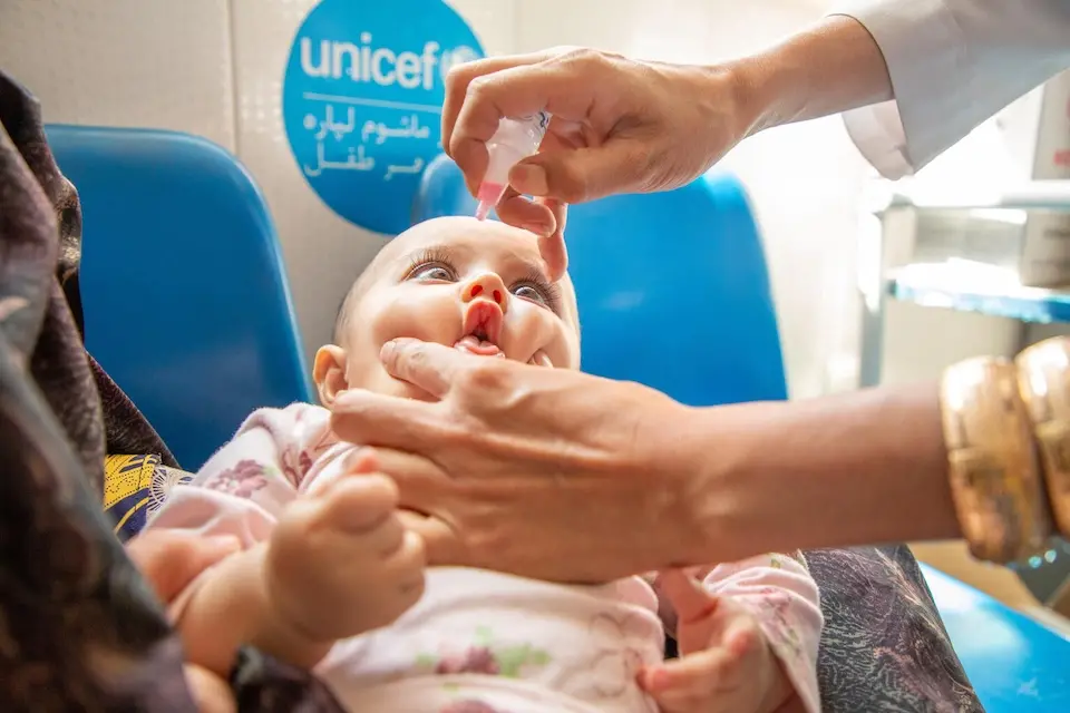A UNICEF-supported vaccinator administers a dose of oral polio vaccine to a baby in Herat province, western Afghanistan. 