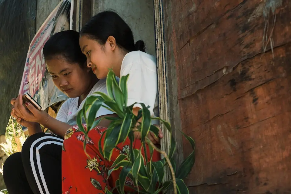 On July, 7, 2023 in Catbalogan, Philippines, Karylle (left), 14, and her younger sister scroll through social media on a cell phone.