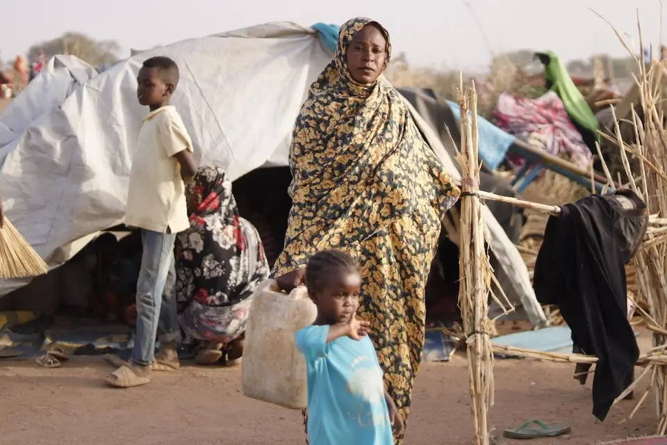 A woman carries a water container outside the tent where she lives with her children in Tawila, Sudan, after fleeing intense fighting in Al Fasher.
