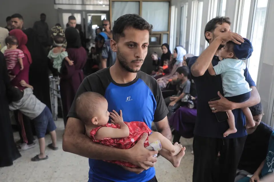 Worried parents holding their children crowd into a UNICEF-supported outpatient nutrition treatment  center in Gaza City.