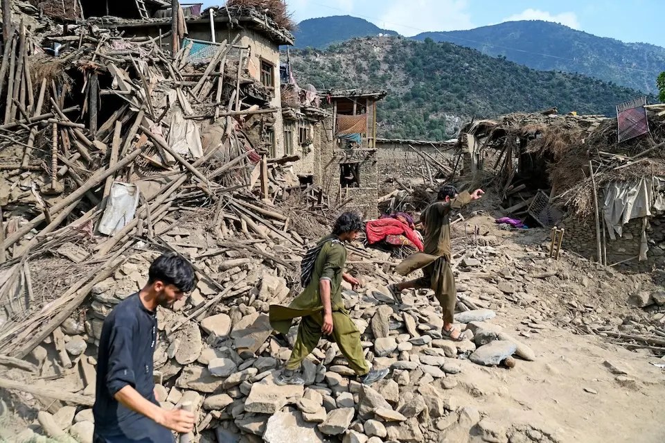 On Sept. 1, 2025, Afghans walk past houses damaged by earthquake in Kunar province, Afghanistan. 