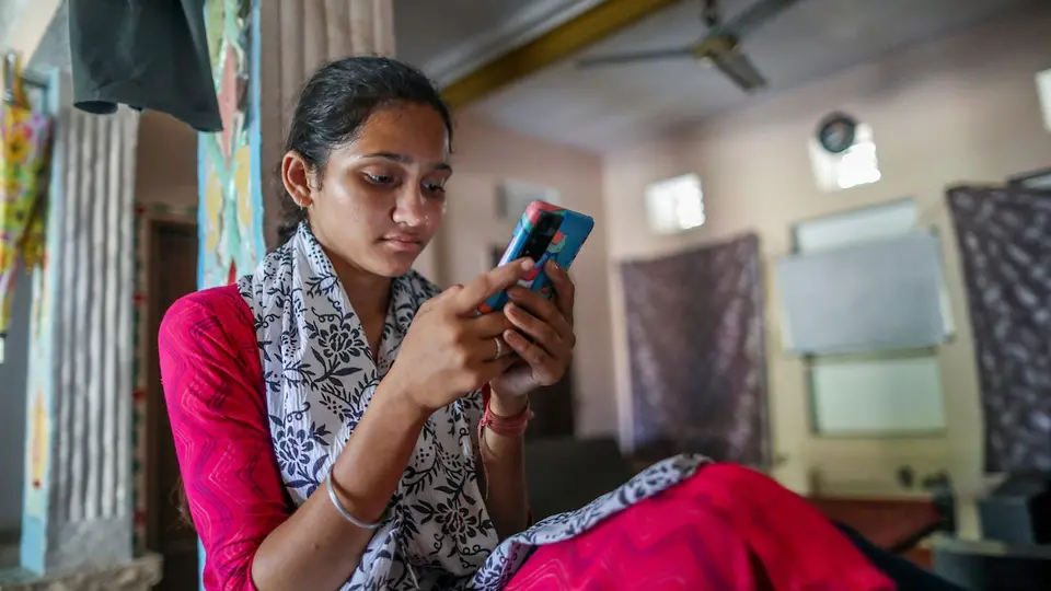 A young woman looking at Passport to Earning on a cell phone