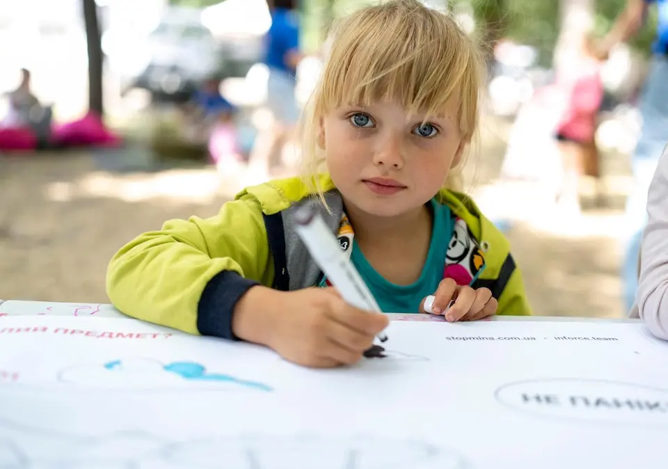 A young girl in Ukraine evacuated from the frontlines takes part in a drawing activity supplied by UNICEF