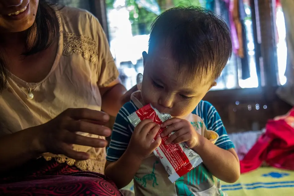 A girl in Myanmar eats food provided by UNICEF to combat malnutrition
