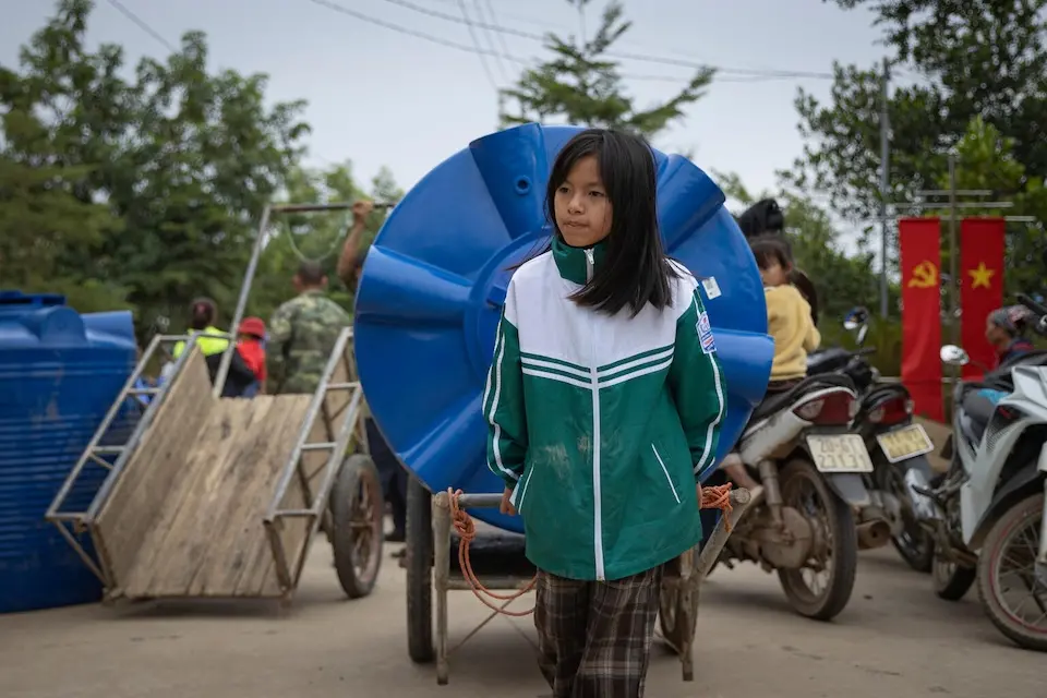 A girl in Vietnam transports a water tank delivered by UNICEF after a series of typhoons