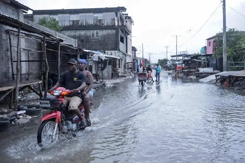 A motorcyclist and his passenger drive in a flooded street after Hurricane Melissa in Les Cayes in the south of Haiti.