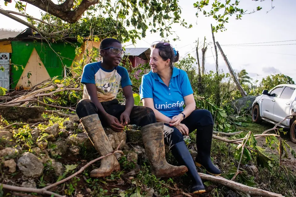 In Jamaica, a boy talks with a UNICEF staff member surrounded by destruction caused by  Hurricane Melissa. 