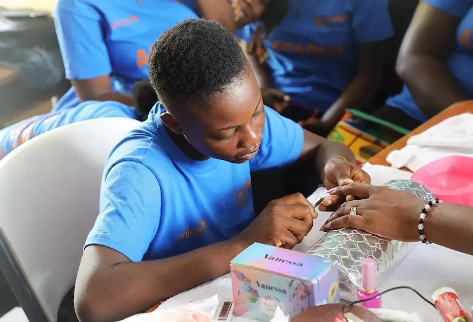 A girl practices giving manicures in a cosmetology workshop in Haiti.