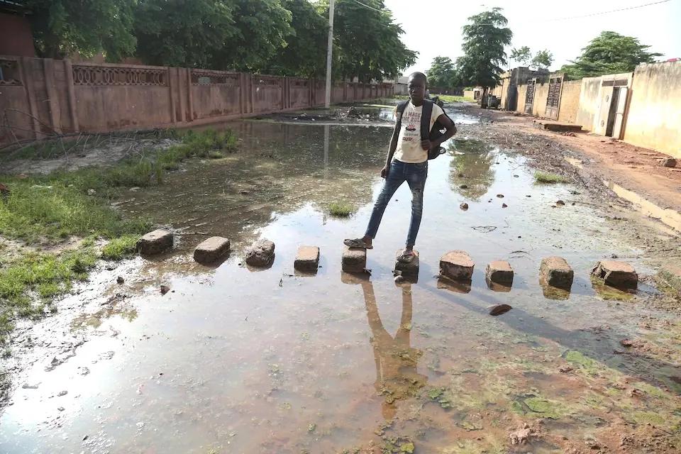 A student stands on blocks placed over floodwaters in Mali in 2024.